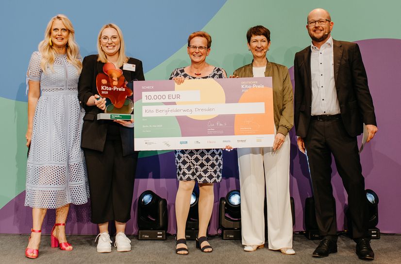 Barbara Schöneberger (li.) übergibt den Preisgeld-Scheck an das Kita-Team.