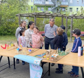Roland Ledwa, Geschäftsführer der Wohnungsgesellschaft Riesa, lässt sich von den Kindern der Grundschule und Kita ihre kreativen Modelle für einen neuen Spielplatz erklären. Foto: Farrar