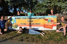 Einige Mitglieder des Skauper Organisationsteams am Werbeplakat am Ortseingang aus Richtung B 101.