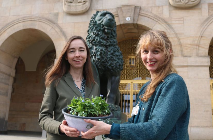 Susan Ebert von der AG Demenz und Sozialbürgermeisterin Dr. Kristin Klaudia Kaufmann setzen mit Vergissmeinnicht vor dem Dresdner Rathaus ein symbolisches Zeichen für alle, die an Demenz erkrankt sind.
