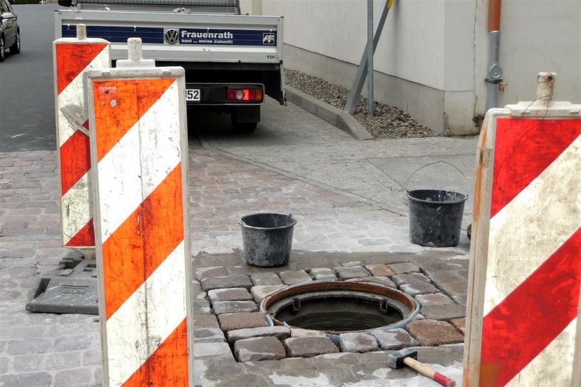 Arbeiten an den neuen Schachtabdeckungen an der Breiten Straße.