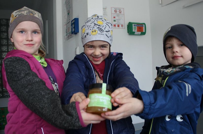 Annika, Anne und Willi zeigen den selbstgemachten Honig.