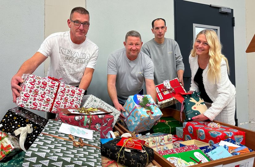 CAPRON-Mitarbeiter präsentieren die Geschenke, die auf die Reise zu den Kindern gehen.
