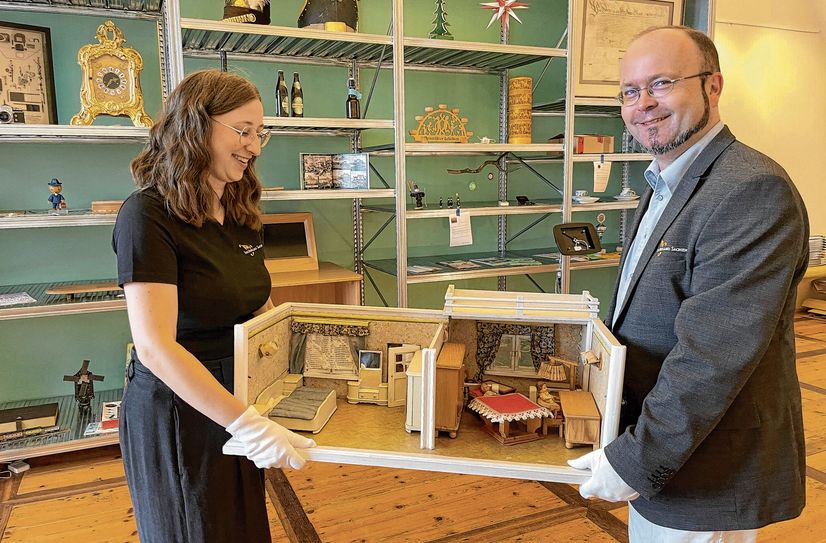Als eine letzte Leihgabe stellen der stellvertretene Schlossleiter der Albrechtsburg Meißen, Falk Dießner und Kulturpädagogin Katharina Banda eine Puppenstube aus Gotha in das »Sachsenregal« der neuen Ausstellung.