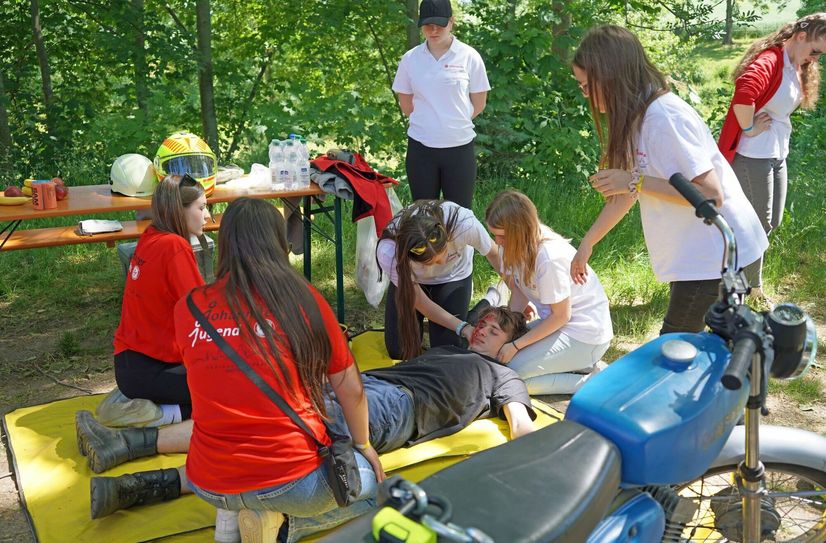 Jugendliche bei der Versorgung eines verletzten Menschen mit Kopfverletzung nach einem Motorradunfall.
