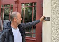 Stifungsmitglied Bill Quaas positioniert die neue Bronzeplakette an der Jahnhalle.