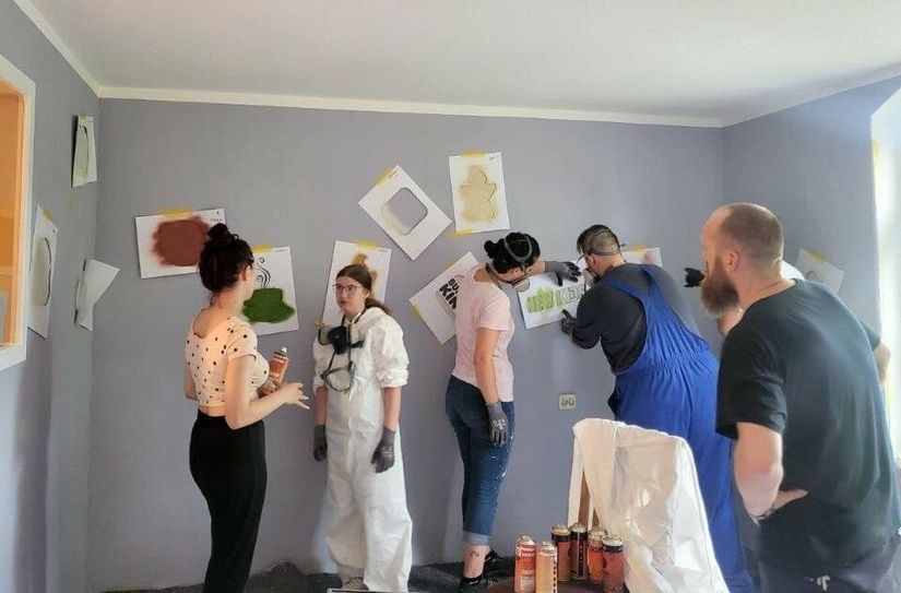 Mit Hilfe von Schablonen werden die Sticker-Graffitis auf die Wand aufgesprüht.