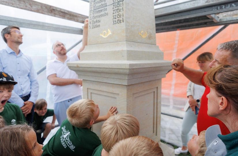 Steinmetzmeister Volker Maaz und Museumsleiter Stefan Auert-Watzik erläutern Oberbürgermeister Ronald Kretzschmar und einigen Hortkindern die historische Funktionsweise der Postmeilensäule.