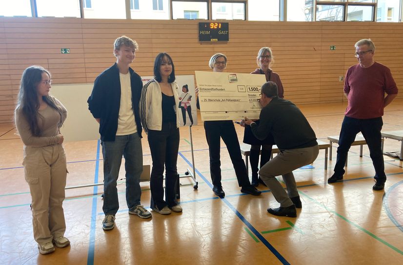 Bildungsbürgermeister Jan Donhauser unterzeichnet den Budget-Scheck, den Schülerrat und Schulleiter der 25. Oberschule entgegennehmen.