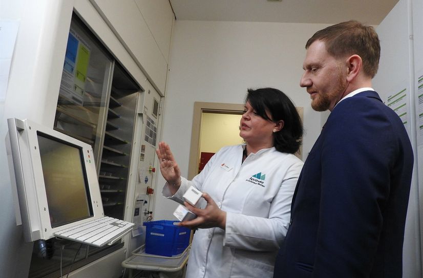 Maret Hoffmann erklärt dem Ministerpräsidenten Kretschmer den Kommissionier-Automaten in ihrer Apotheke.