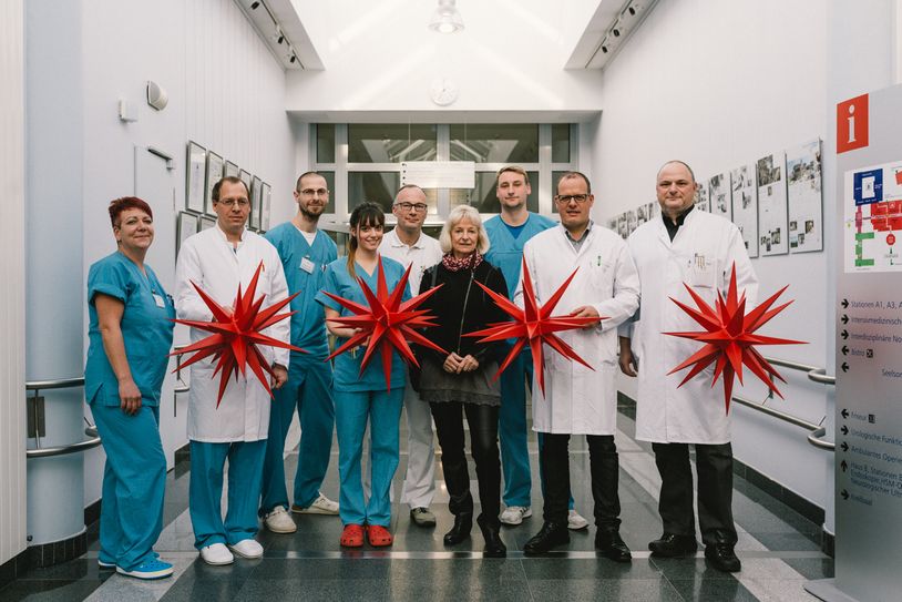 Chefärzte (in weiß v.l.n.r.: Dr. Rüdiger Karbaum, Dr. Kersten Guthke, Dr. Axel Geide, Dr. Marcus Eif) und Pflegekräfte aus vier Kliniken nehmen die roten Herrnhuter Sterne in Empfang. Mitte in „zivil“ Beate Freudenberg. Foto: Städtisches Klinikum Görlitz gGmbH
