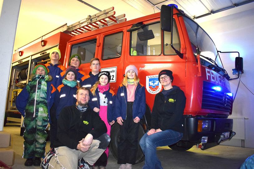 Ein Teil der Jugendfeuerwehr sowie Gemeindewehrleiter Michael Wuschansky und Jugendfeuerwehrwartin Christina Wuschansky haben sich vor dem Feuerwehrfahrzeug aufgestellt - sie benötigen Unterstützung für die neuen Räumlichkeiten.