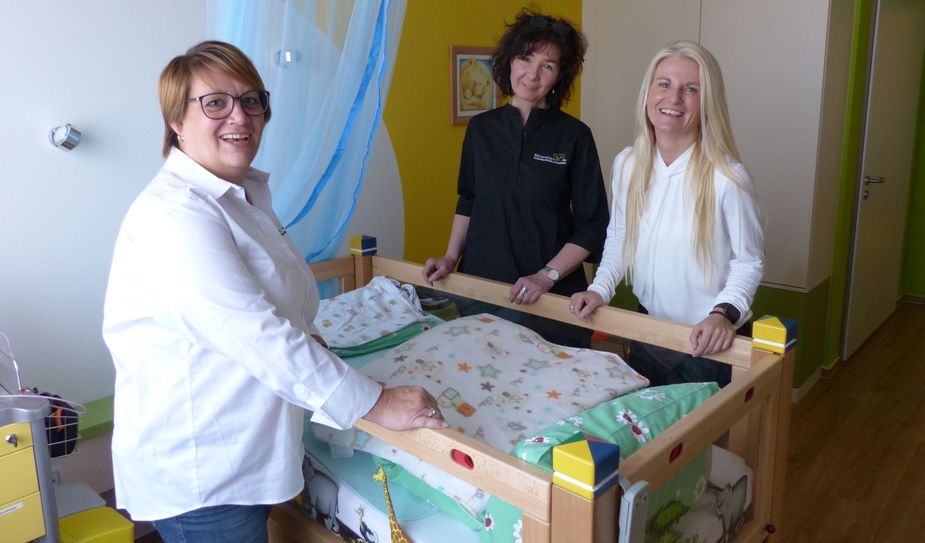 Jaqueline Thümmrich (Heim- und Pflegedienstleiterin), Uta Meier (pädagogische Leiterin) und Geschäftsführerin Nicole Tobias an einem Kinderbett. Foto: Meeco Communication