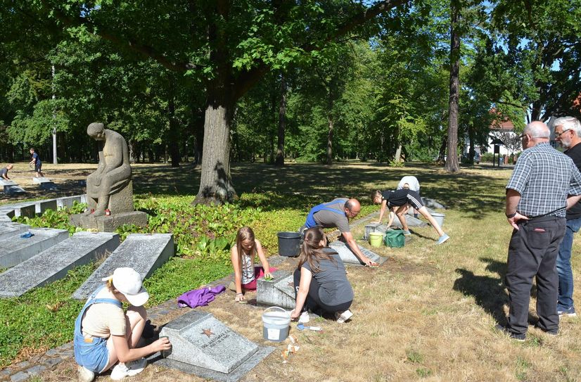 Schüler der fünften und sechsten Klasse des Erwin-Strittmatter-Gymnasiums reinigen die Grabsteine der gefallenen deutschen und russischen Soldaten auf dem Georgenbergfriedhof.