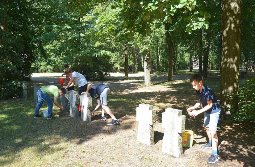 Schüler der fünften und sechsten Klasse des Erwin-Strittmatter-Gymnasiums reinigen die Grabsteine der gefallenen deutschen und russischen Soldaten auf dem Georgenbergfriedhof.