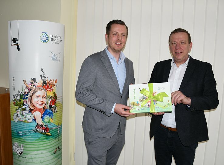 Landrat Christian Jaschinski (r.) übergab dem neuen Geschäftsführer der Tourismus-Marketing GmbH, Christian Woronka, ein kleines Willkommensgeschenk und sicherte ihm seine volle Unterstützung bei den geplanten Vorhaben zu.
 Foto: Pressestelle Kreisverwaltung