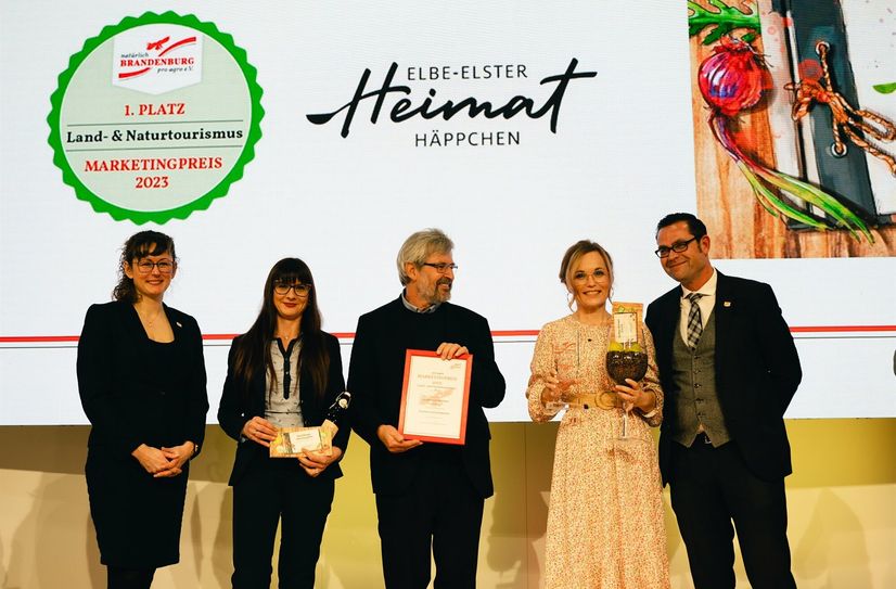 Die Übergabe des Preises durch den Minister für Landwirtschaft, Umwelt und Klimaschutz Axel Vogel (i.d.M.) an Janine Niederstraßer, Marketingkoordinatorin des Landkreises Elbe-Elster (2.v.r) und Jana Oppitz vom Brauhaus Finsterwalde(2v.l.), welche stellvertretend für die beteiligten Gastronomen und Siegelträger vor Ort war, mit auf der Bühne zur Gratulation Kai Rückewoldt (1.v.r) Geschäftsführer von pro Agro und Hanka Mittelstädt, Vorsitzende von pro Agro e.V. (1v.l.).
