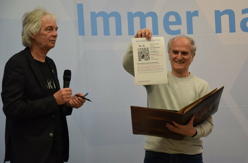 Waldemar Cierpinski zeigt sein Blatt, auf dem er sich im Goldenen Buch der Marathon Hall of Fame des LTL verewigt. Daneben steht Manfred Grüneberg.