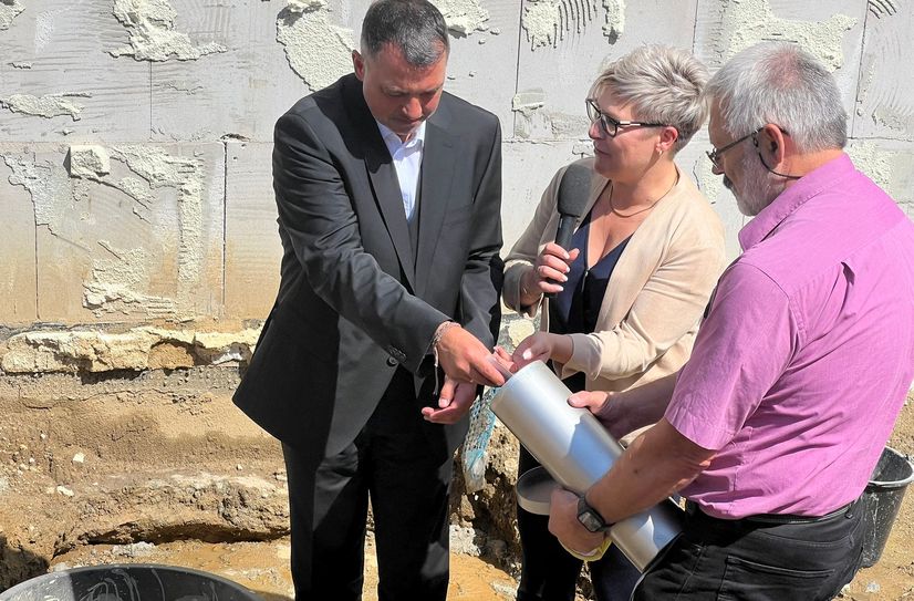 Landrat Udo Witschas (l.) befüllt die Kartusche zur Grundsteinlegung mit aktuellen Zeitdokumenten.