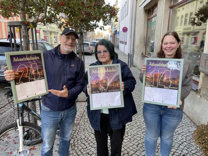 Präsentieren drei der 24 eingerahmten Adventskalenderblätter (vo.li.na.re.): Fred Bauer, Jutta Dzielak und Isabel Reichel vom Schuhhaus Reichel.