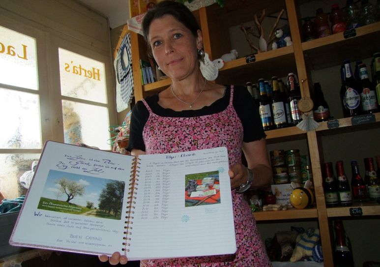 Im kleinen Selbstversorgerladen zeigt Projektmanagerin Ina Schreiber die Kladde, in die sich die Pilger eintragen.