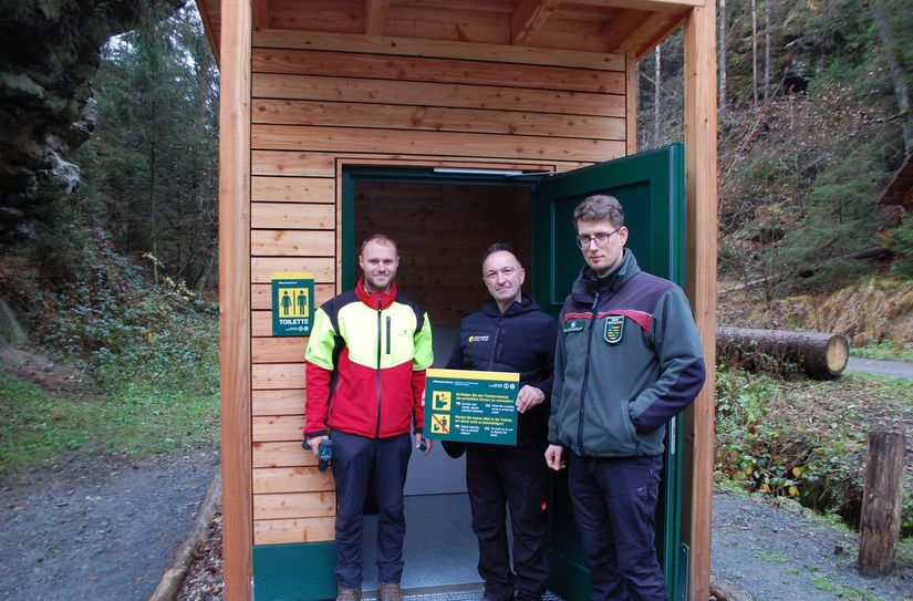 Projektkoordinator Martin Aulitzky (Nationalpark- und Forstverwaltung Sächsische Schweiz), Zimmerer Stanley Michael und Alexander Nowak, Leiter der Nationalparkwacht (v. l. n. r.) bei der Einweihung der Waldtoilette an der Neumannmühle.