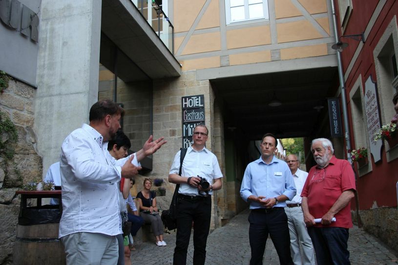 Unternehmer Sven-Erik Hitzer (l.) spricht über Schmilka. Jurymitglied Peter Schawerda (r. ) und Bürgermeister Thomas Kunack (3.v.r.) hören interessiert zu. Foto: Schramm