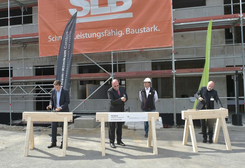 Wie es der Brauch verlangt, schlagen Dr. Markus Niggemann, Vorsitzender des Aufsichtsrates des Carl-Thiem-Klinikums Cottbus, Dr. Dirk Große Meininghaus, Chefarzt der Rhythmologie der 1. Medizinische Klinik und Dr. Götz Brodermann, Geschäftsführer des Carl-Thiem-Klinikums (v.l.n.r.), den Zimmermannsnagel zum Richtfest ein. Foto: Peter Aswendt