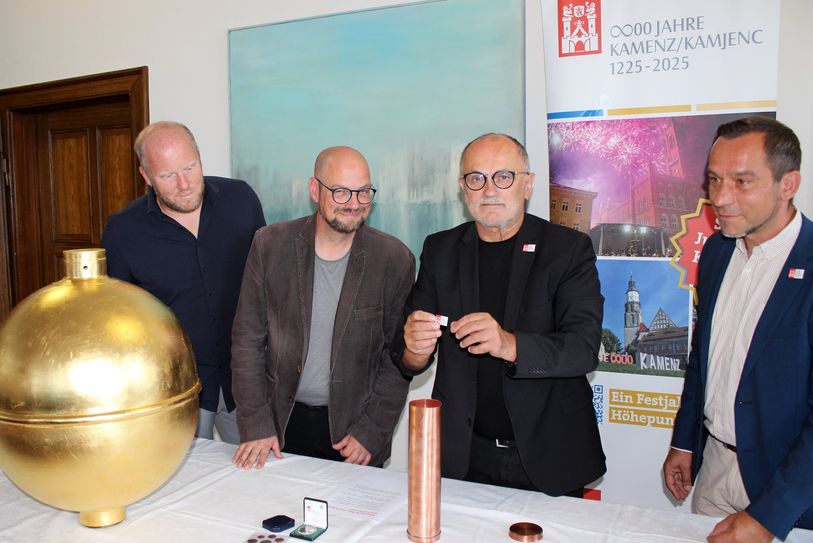 Im Beisein von Baudezernent Michael Preuß (l.), dem Stadtarchivar Thomas Binder (2.v.l.) und Projektkoordinator Maik Fabisch (r.) befüllt Oberbürgermeister Roland Dantz (2.v.r.) die Kartusche für die Turmkugel des Kamenzer Rathauses.