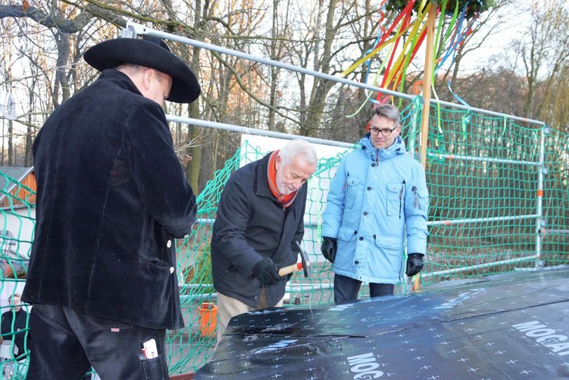 Manfred Schäfer, Vorsitzender des Tierpark Fördervereins, schlägt den letzten Nagel ins Gebälk, nachdem Zimmermeister Andreas Görner den Richtspruch spricht. Karsten Pinetzki (rechts) begleitet bei der Stadt Finsterwalde das Projekt. Foto: Stadtverwaltung Finsterwalde