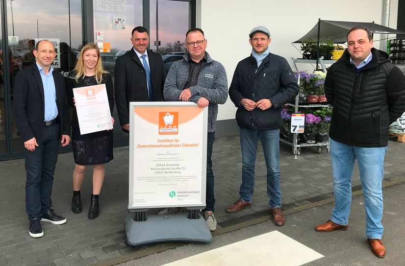 Der Einzelhändler Olaf Schneider (mitte) nimmt die Auszeichnung im Beisein des Handelsverbandes, der Edeka-Gruppe und politischen Akteuren entgegen.           Foto: meeco