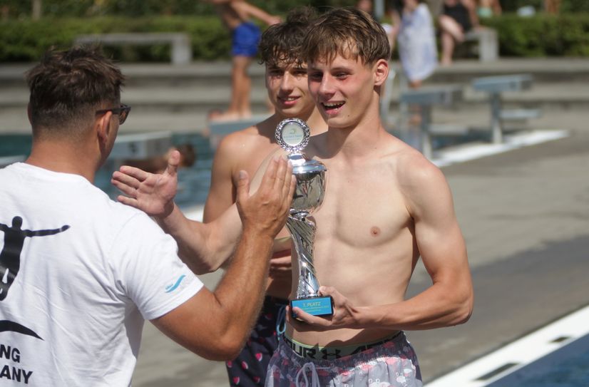 Fabian Bartzsch nimmt den Siegerpokal im Arschbomben-Wettbewerb entgegen.