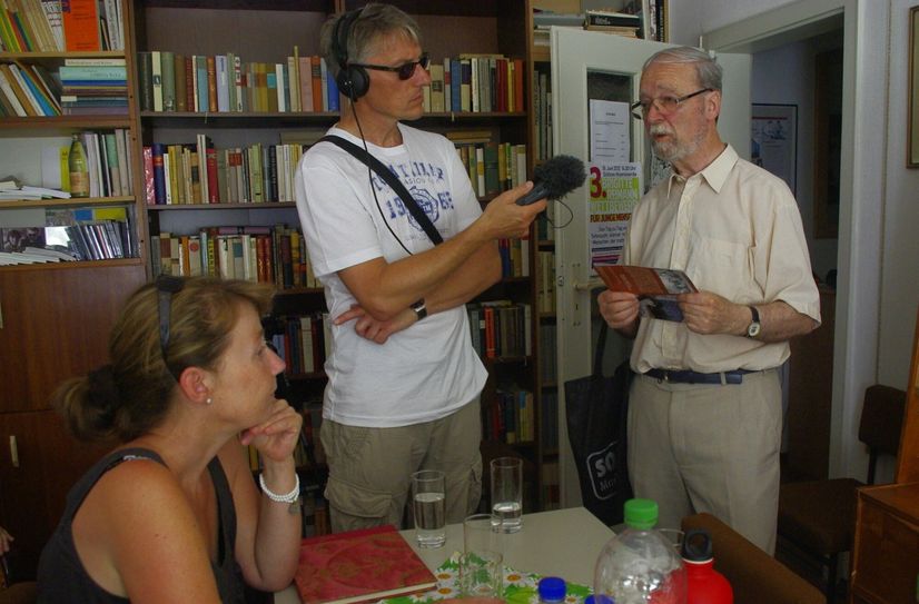 Der ehemalige Vorsitzende des Kunstvereins, Martin Schmidt, spricht mit dem Journalisten Mirko Schwanitz in der Begegnungsstätte. Im Hintergrund sind die Regale mit der Literatur zu sehen, die auf dem Bücherflohmarkt veräußert werden.