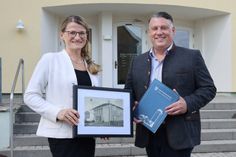 Anne Francken, kaufmännische Geschäftsführerin der BASF Schwarzheide GmbH übergibt das Bilderarchiv an Schwarzheides Bürgermeister Christoph Schmidt.