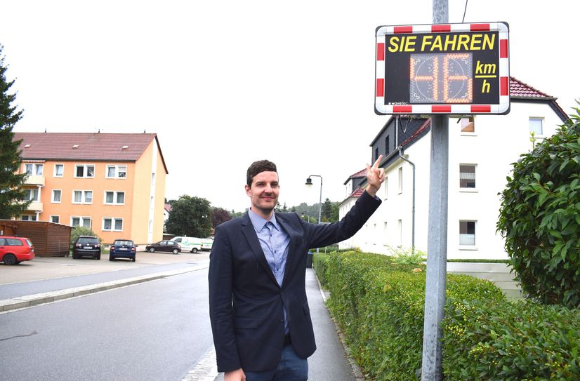 Bürgermeister Achim Wünsche zeigt auf die neue Geschwindigkeitsanlage, die zuerst im Ortsteil Schmölln installiert wurde.