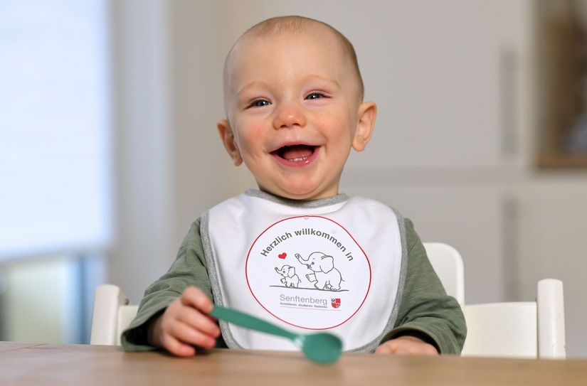 Der einjährige Noah trägt als echter Senftenberger beim Warten auf den Gemüsebrei schon mal das neue Senftenberger Stadt-Lätzchen. Genauso ein Lätzchen bekommen alle Minis, die zum Baby-Empfang des Bürgermeisters am 28. Februar ins Kulturschiff  in den Familienpark Großkoschen kommen.