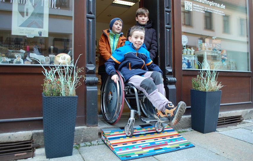 Richard, Endrik und Adrian (v. l. n. r.) probieren die von ihnen gebaute erste LEGO-Rampe für die Pirnaer Altstadt am Eingang des KiP-Lädchens des Citymanagements aus.