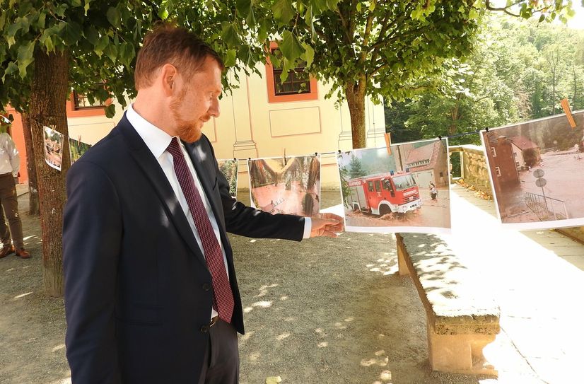 Ministerpräsident Michael Kretschmer betrachtet die Fotos, welche die Flutkatastophe in Weesenstein von 2002 dokumentieren.