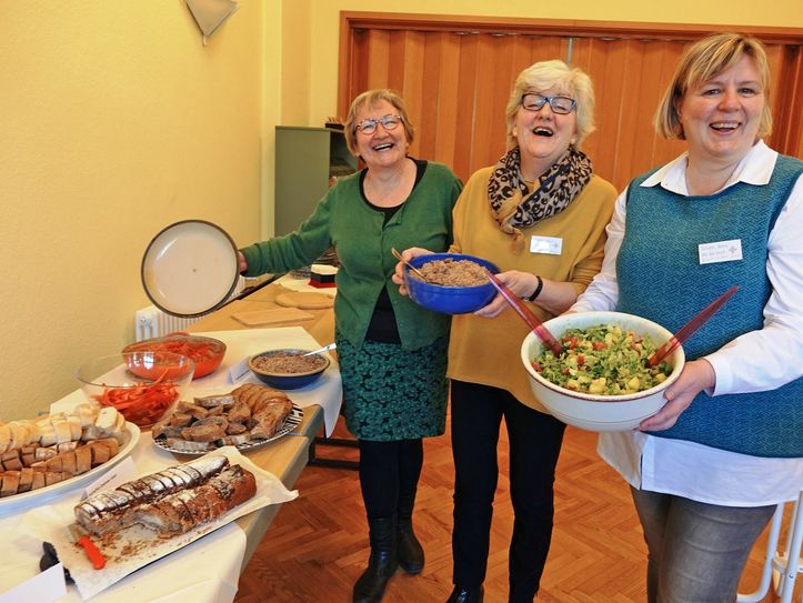 Marlies Siegert (li.), Christine Bartsch (Mitte) und Birgit Walter-Goers (re.) lüften die Topfdeckel und luden am Samstag unter dem Motto „Kommt, alles ist bereit!“ zum slowenischen Buffet ein. Foto: Franziska Dorn/Evangelischer Kirchenkreis Niederlausitz