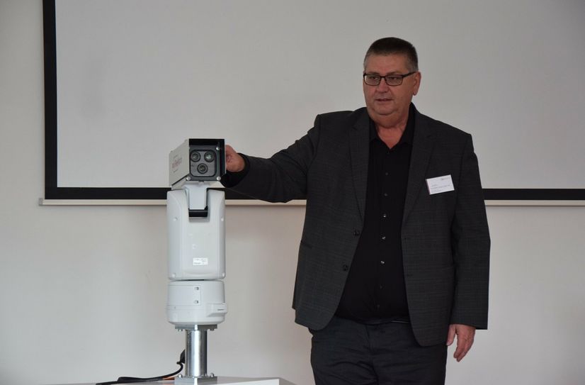 Dr. Kurt Winter erklärt die Sensoreinheit, die am Wachturm Bilder für die Forstmitarbeiter aufnimmt.