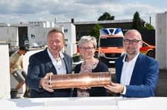 Feierlicher Moment in Großthiemig: Landrat Christian Jaschinski, Amtsdirektorin Kathleen Wilken und Werkleiter Sebastian Weiss (v.l.n.r.) versenken gemeinsam eine kupferne Zeitkapsel im Grundstein der neuen Rettungswache – ein Zeichen für Zukunft und Engagement im Rettungsdienst.