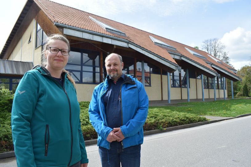 Hochbau-Verantwortliche Anja Burkhardt und Bürgermeister Alexander Fischer stehen vor der Turnhalle, die die Gemeinde gern entwickeln und sanieren möchte.