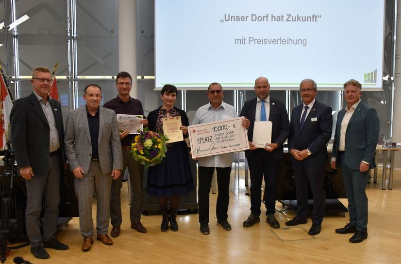 Landrat Harald Altekrüger (2.v.r.) und Jens Gerards (2.v.l.) von der Sparkasse Spree-Neiße (2.v.l.) überreichten die Urkunde und das Preisgeld an die Vertreter des Siegerdorfes.