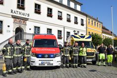 Kameraden der Berufsfeuerwehr präsentieren den neuen Einsatzleitwagen und den Rettungstransportwagen vorm Rathaus.