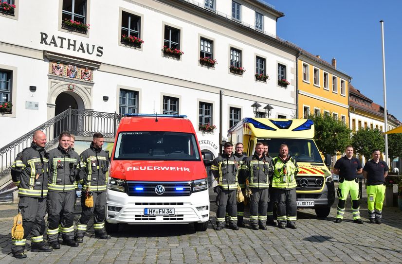 Kameraden der Berufsfeuerwehr präsentieren den neuen Einsatzleitwagen und den Rettungstransportwagen vorm Rathaus.