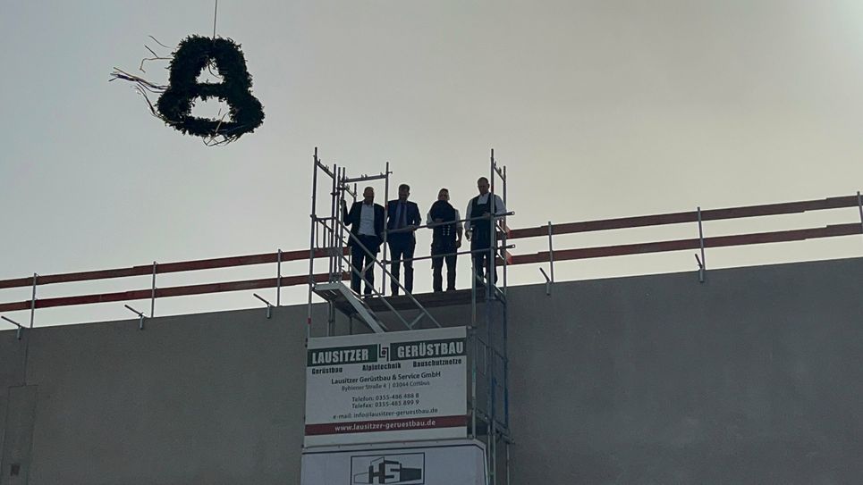 Richtspruch auf dem Dach: Vorstandssprecher Mark Rosenkranz (1.v.l.) und Cottbuser Oberbürgermeister Tobias Schick (2.v.l.) mit Zimmermännern vom SCHULTE Bauunternehmen.