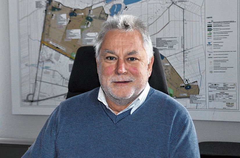 Tilo Hönicke an seinem Arbeitsplatz im Rathaus, vor dem Plan des Flugplatzgeländes.