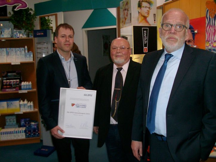 Aufsichtsratsvorsitzender Hans-Wilm Sternemann (r.) überreicht Volkmar Schnell (M.) und seinem Sohn Torsten den Innovationspreis 2016 des Augenoptikerverbundes IGA OPTEC. Foto: emo
