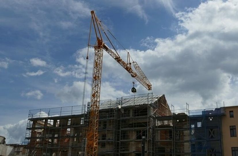 Die Richtkrone schwebt an einem Baukran über einem der neun Häuser, die im Rahmen der Erweiterung des Landratsamtes saniert werden.