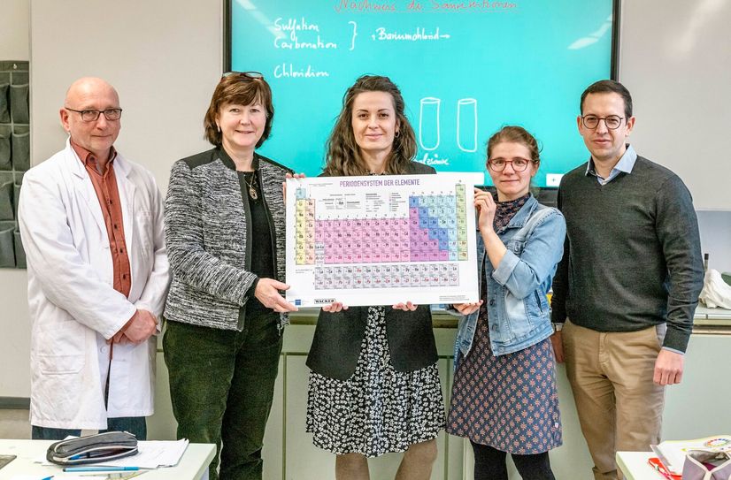 Spendenübergabe im Chemie-Kabinett der Triebischtalschule: Chemie-Lehrer Thoralf Brumm, Schulleitung Steffi Wenzel, Standortkommunikatorin des WACKER-Standorts Nünchritz Janine Kmitta, Chemie-Lehrerin Anne-Kathrin Brack und Geschäftsführer Kommunikation, Bildung und Nachhaltigkeit der Nordostchemie-Verbände Fabian Hoppe (v.l.). Symbolisch wird ein großes Periodensystem überreicht und damit die Bedeutung der Investition in die Chemie-Bildung junger Menschen unterstrichen.